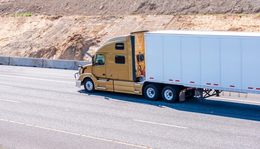 Yellow truck hauling a dry van trailer